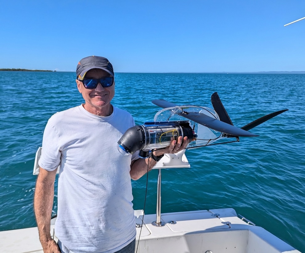 Dr Brett Kettle holding a Vertigo3 glider on a boat.
